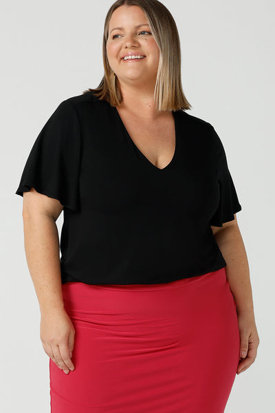 Close up of a flutter sleeve, black top for work and casual wear, this tailored top is worn by a size 18 curvy woman. Made in Australia, shop women's black tops online at Australian and New Zealand women's clothing brand, Leina & Fleur.