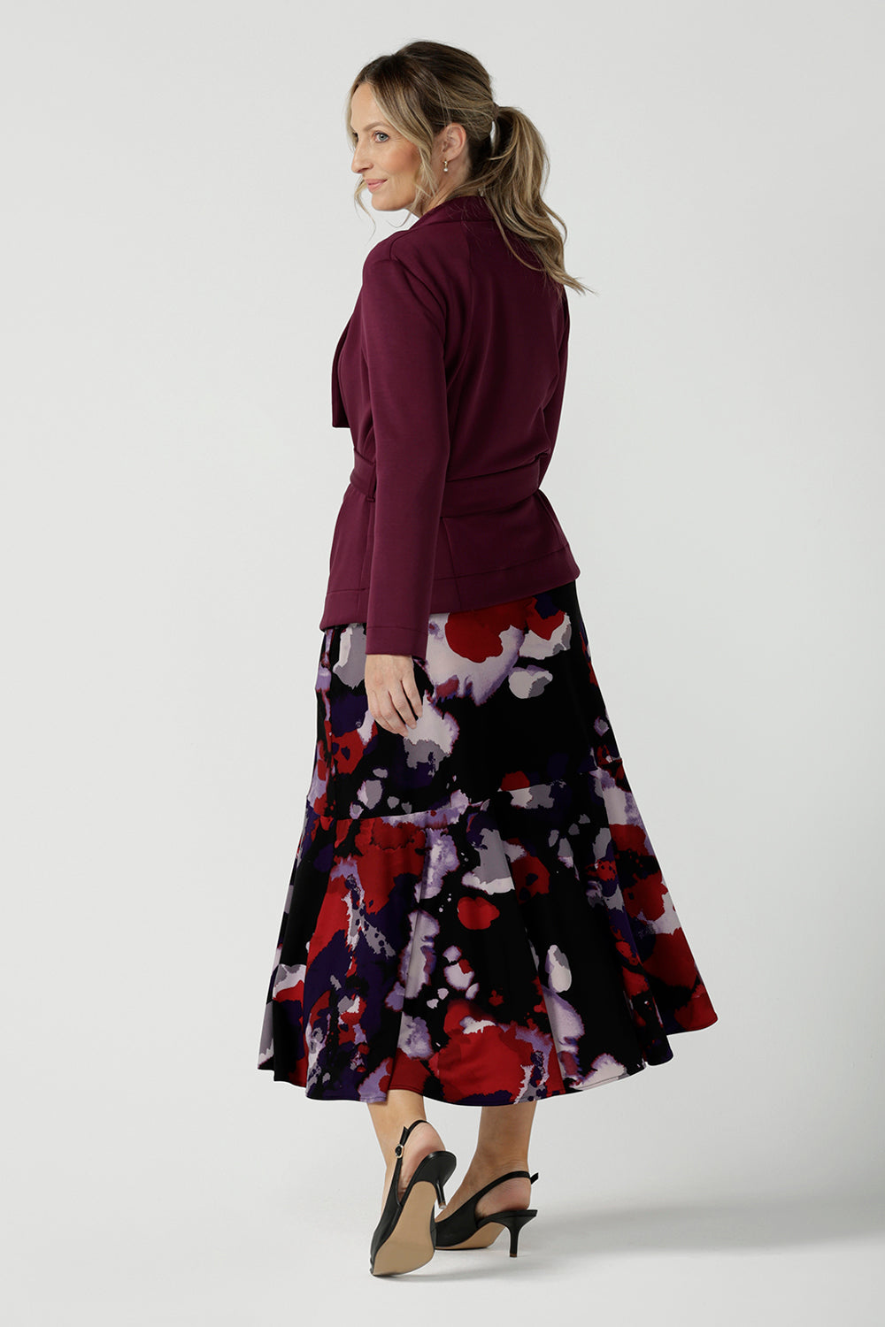 Back view of a size 10 woman wears the Lyndon Jacket in Wine a made in Australia jacket in comfortable and easy care modal fabric. Made in Australia for women size 8 - 24. Styled back with a Berit skirt in the Fitzroy print.