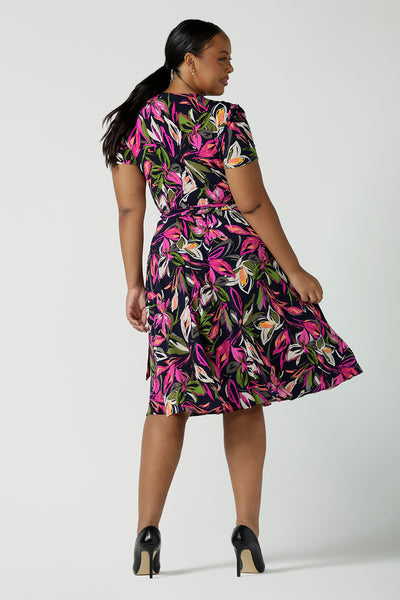 Back view of a size 16 woman wears the Maree dress in Vivid Flora. Short sleeve functioning wrap dress. Knee length dress great for petite heights. Work corporate to weekend wear. Travel friendly. Made in Australia for women size 8 - 24.