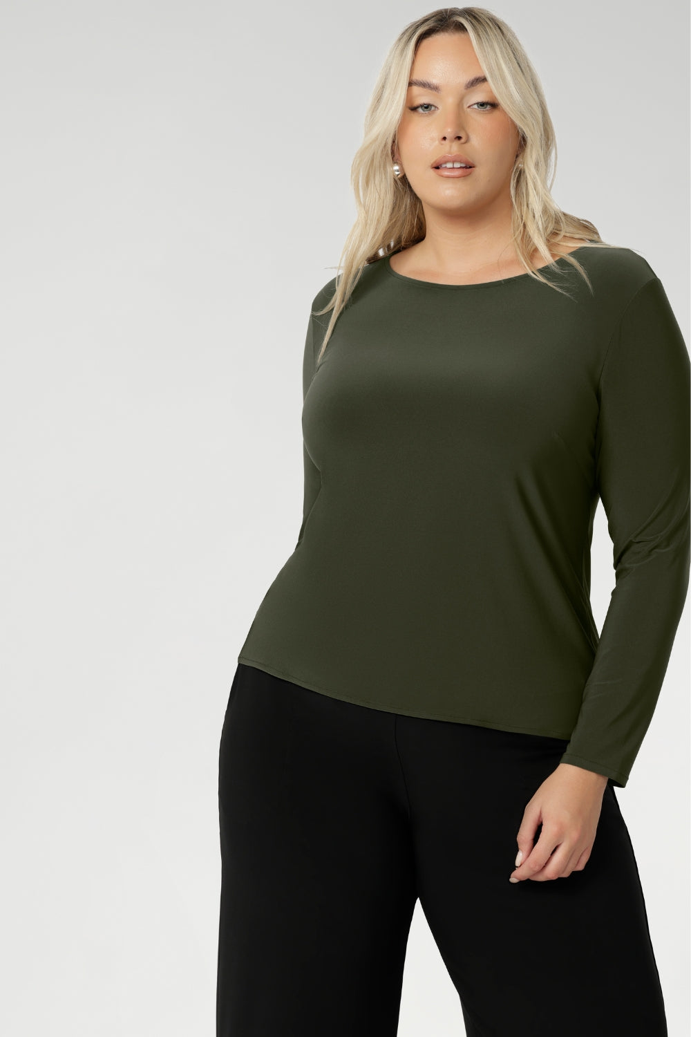 Perfect layering top as the weather cools. The close-to-body fit is enhanced by bust darts for a flattering silhouette, while long sleeves offer warmth. The straight hemline at the front and longer curved hemline at the back add a modern touch to this versatile piece. Available in sizes 8 to 24. Plus size woman wears her top with wide leg black pants.