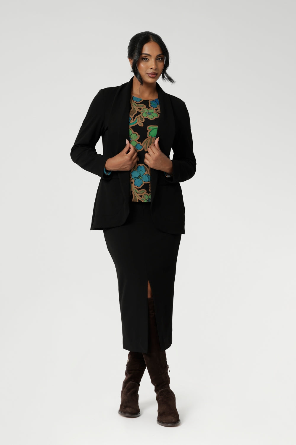 Size 10 woman wears her floral top paired with midi length skirt and black easy care blazer. The long sleeves provide added warmth, while the straight hemline at the front and curved hemline at the back, which sits longer, give it a modern touch.