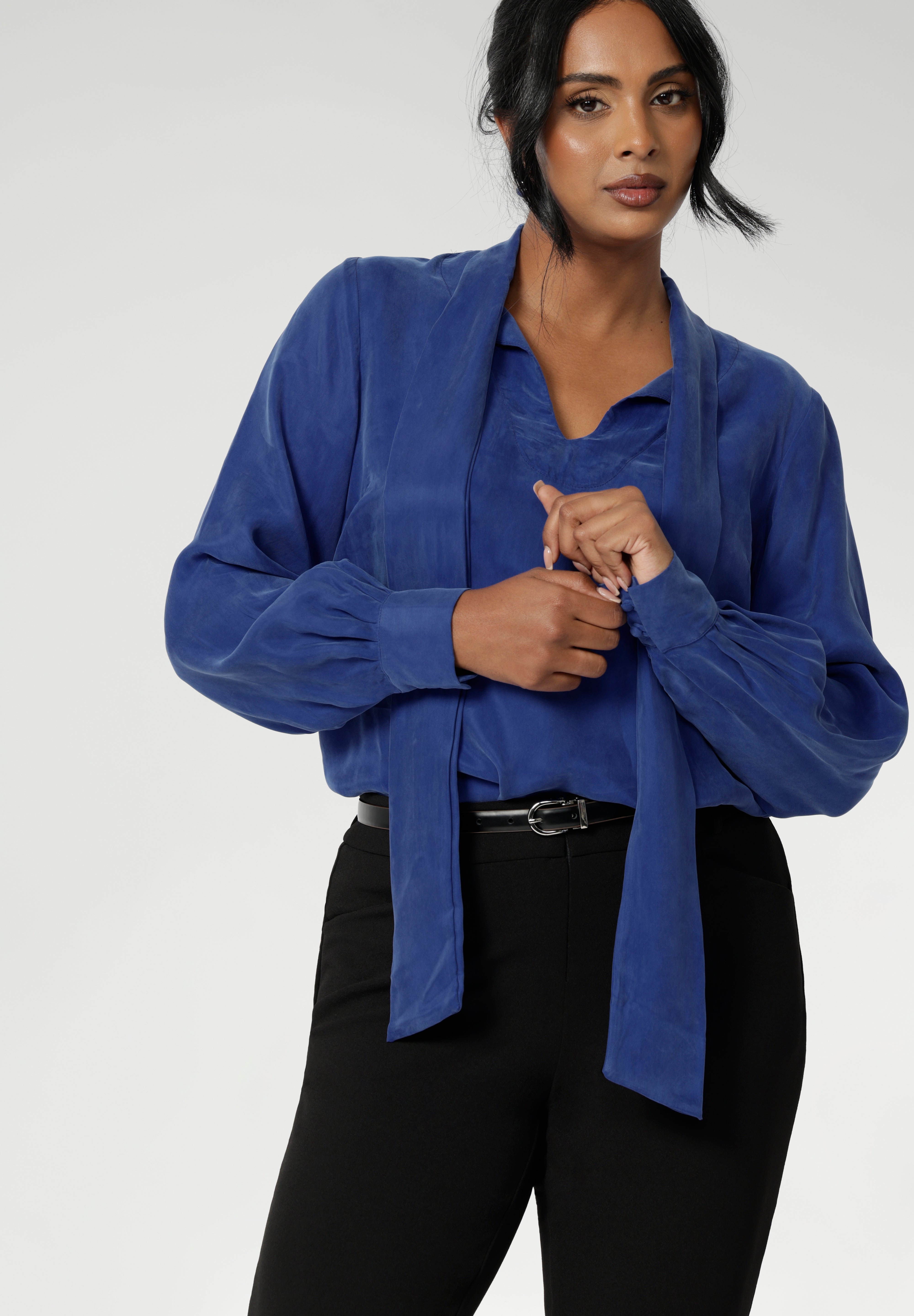 The Matisse Shirt in Cobalt is a pull-on style with a tie neckline, crafted from soft, fluid fabric. Blouson sleeves and buttoned cuffs add a polished finish.