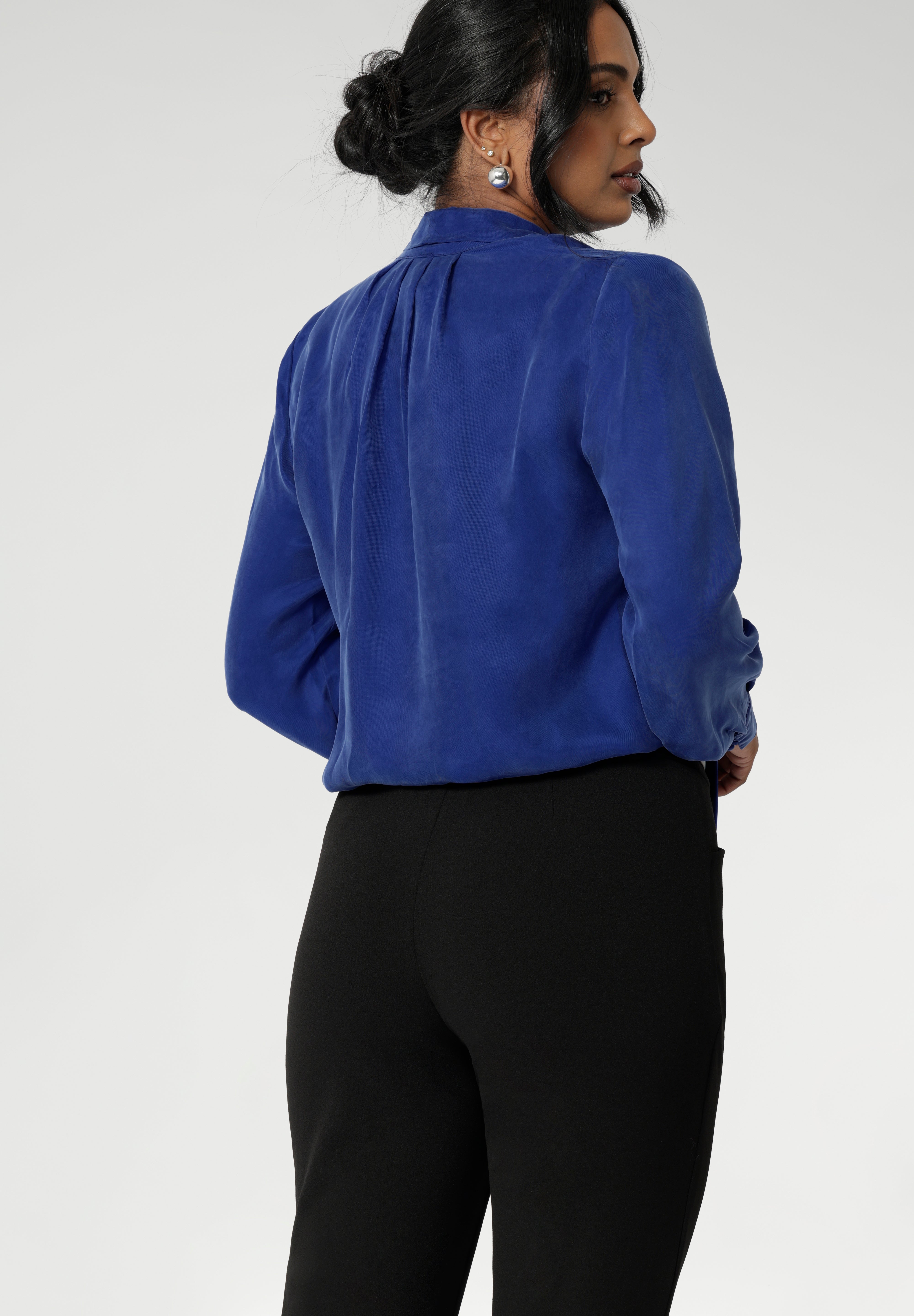 The Matisse Shirt in Cobalt is a pull-on style with a tie neckline, crafted from soft, fluid fabric. Blouson sleeves and buttoned cuffs add a polished finish. Matisse is a semi-fitted pull on style V-neckline shirt with extended neck ties, back pleats and bishop sleeves. Crafted from suede touch Tencel that has a luxurious feel and drape. Proudly made in Australia in sizes 8-24.