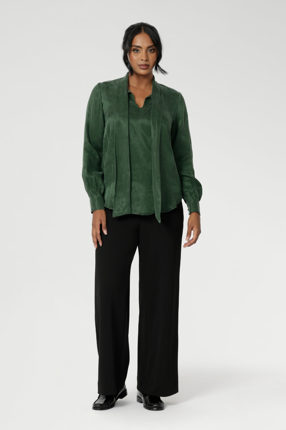Crafted from suede touch Tencel that has a luxurious feel and drape. Proudly made in Australia in sizes 8-24. The Matisse Shirt in Deep Green is a pull-on style with a tie neckline, crafted from soft, fluid fabric. Blouson sleeves and buttoned cuffs add a polished finish. Matisse is a semi-fitted pull on style V-neckline shirt with extended neck ties, back pleats and bishop sleeves.