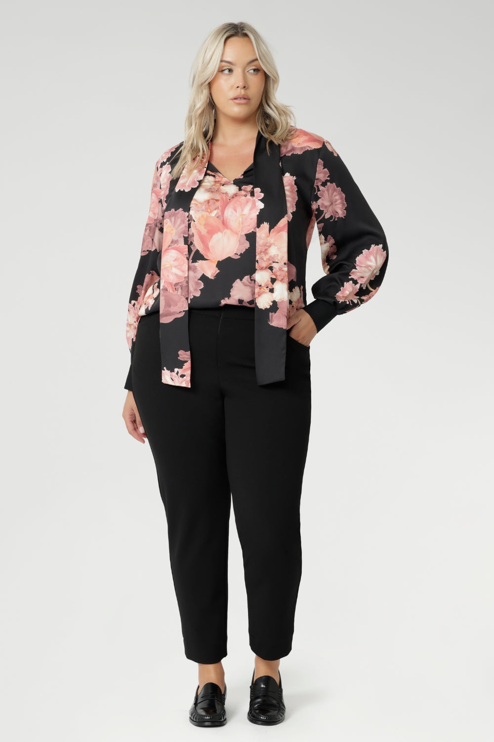 While the fabric offers no stretch, its fluid drape ensures a flattering, comfortable fit. Ideal for pairing with tailored separates or dressed down with denim, the Matisse Shirt brings timeless romance to your wardrobe. Plus size woman wears floral blouse tucked into her straight leg pants.