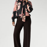 While the fabric offers no stretch, its fluid drape ensures a flattering, comfortable fit. Ideal for pairing with tailored separates or dressed down with denim, the Matisse Shirt brings timeless romance to your wardrobe. Plus size woman wears floral blouse tucked into her straight leg pants.