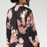 Crafted from a soft, fluid satin rayon fabric, this semi-fitted shirt features a pull-on design with a graceful V-neckline and extended neck ties that can be styled in multiple ways. The romantic floral print blooms across a black satin base, with delicate pink tones adding depth and softness to the look.