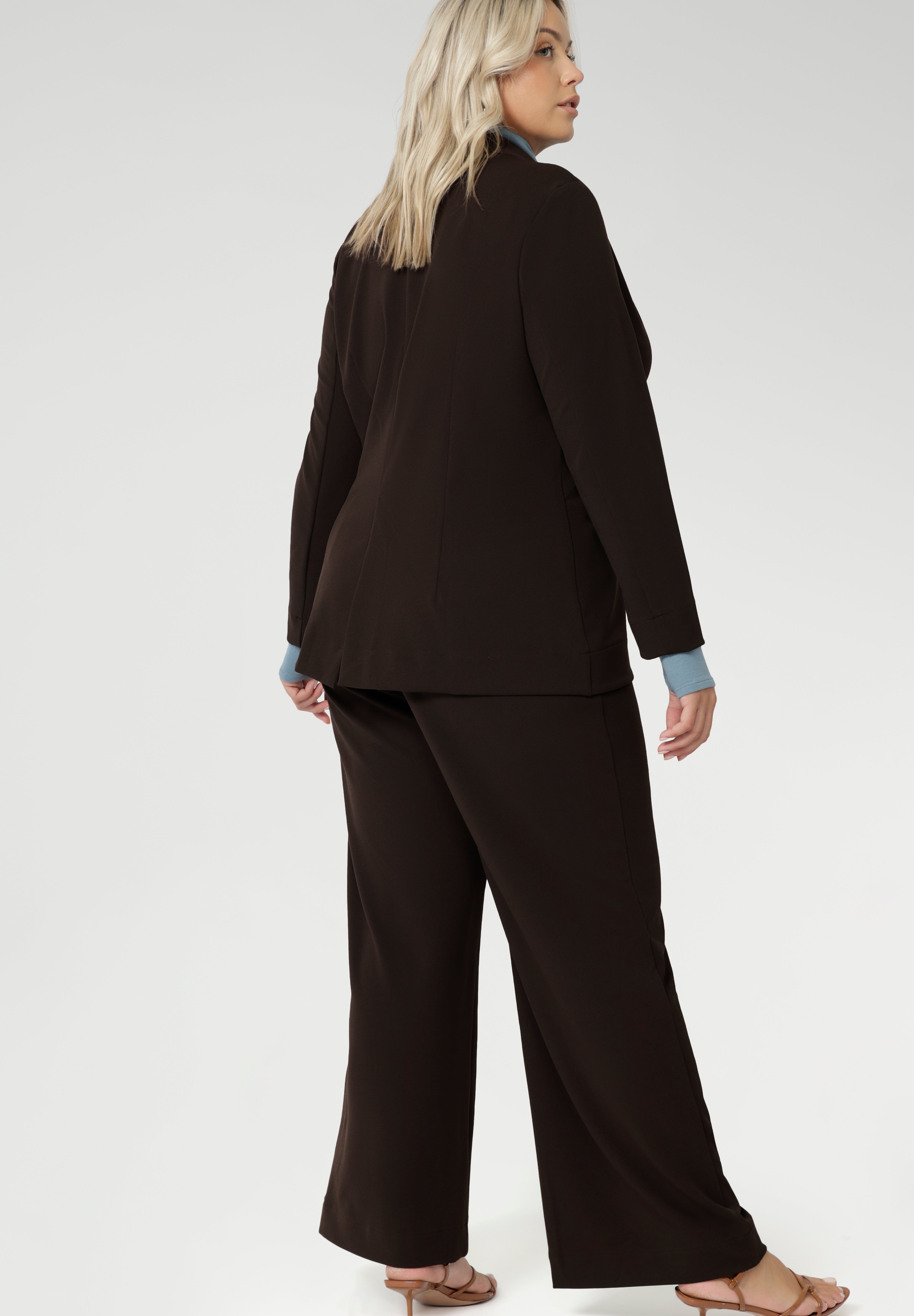 Merit is a tailored and light weight woman's workwear blazer that offers elevated style. Size 18 woman wears workwear blazer in cocoa colour, crafted from quality scuba crepe fabric. Long blazer offers full body stretch and comfort. Australia made by Leina & Fleur in sizes 8-24.