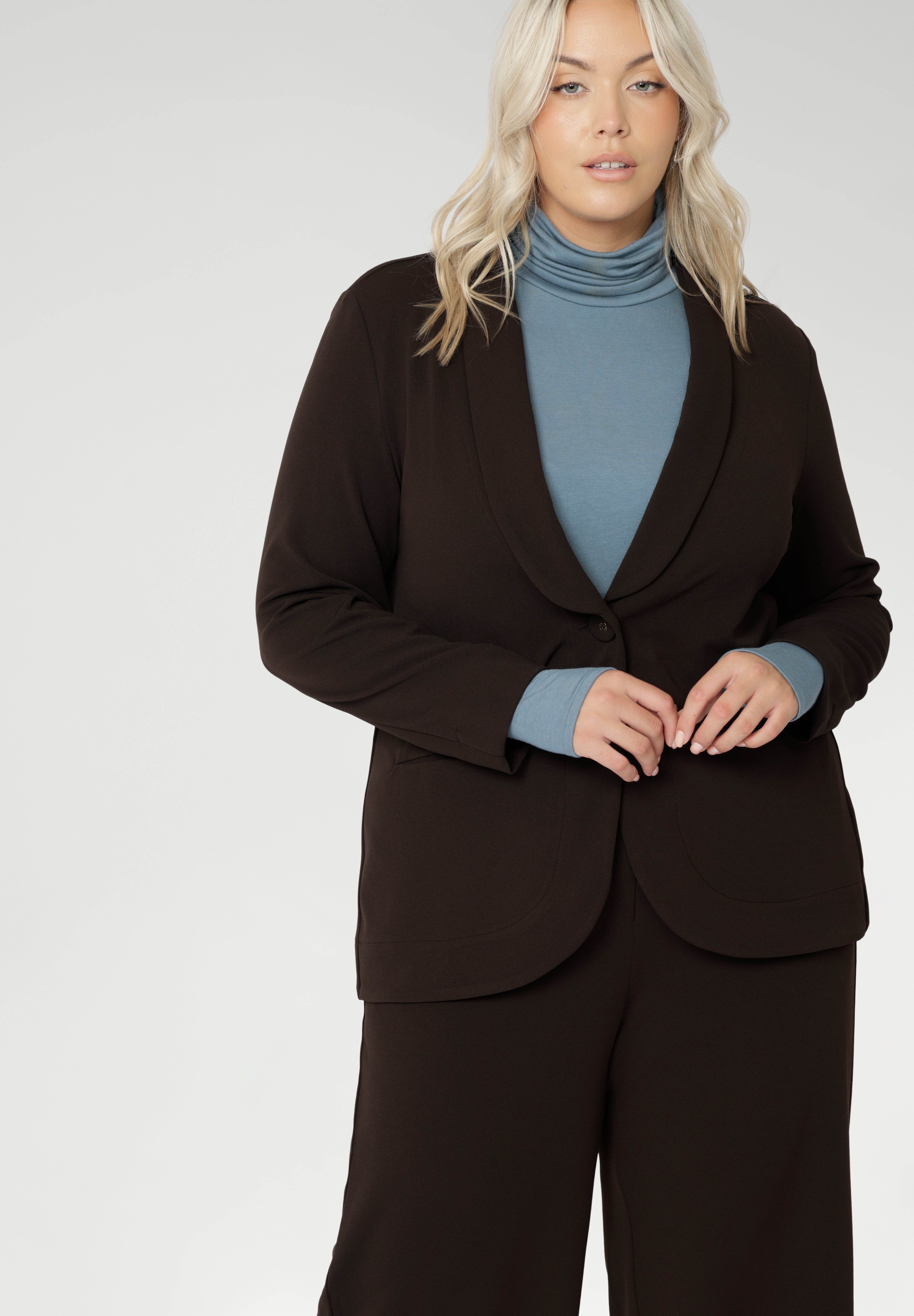 Merit is a tailored and light weight woman's workwear blazer that offers elevated style. Size 18 woman wears workwear blazer in cocoa, crafted from quality scuba crepe fabric. Long blazer offers full body stretch and comfort. Australia made by Leina & Fleur in sizes 8-24.