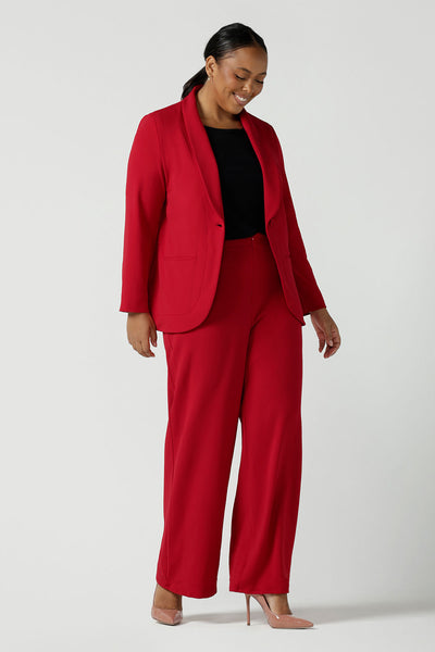 A size 18 woman wears the Merit Blazer in Flame, a textured scuba crepe blazer with button front. Curved hemline and front pockets. Made in Australia for women size 8 - 24.