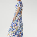 The empire waistline and twist-front V-neck create a naturally flattering shape, while flutter sleeves and a double-layered bodice provide elegant structure and ease. A flowing skirt with an overlap slit adds graceful movement and a touch of allure—perfect for weddings, garden parties, and special celebrations.