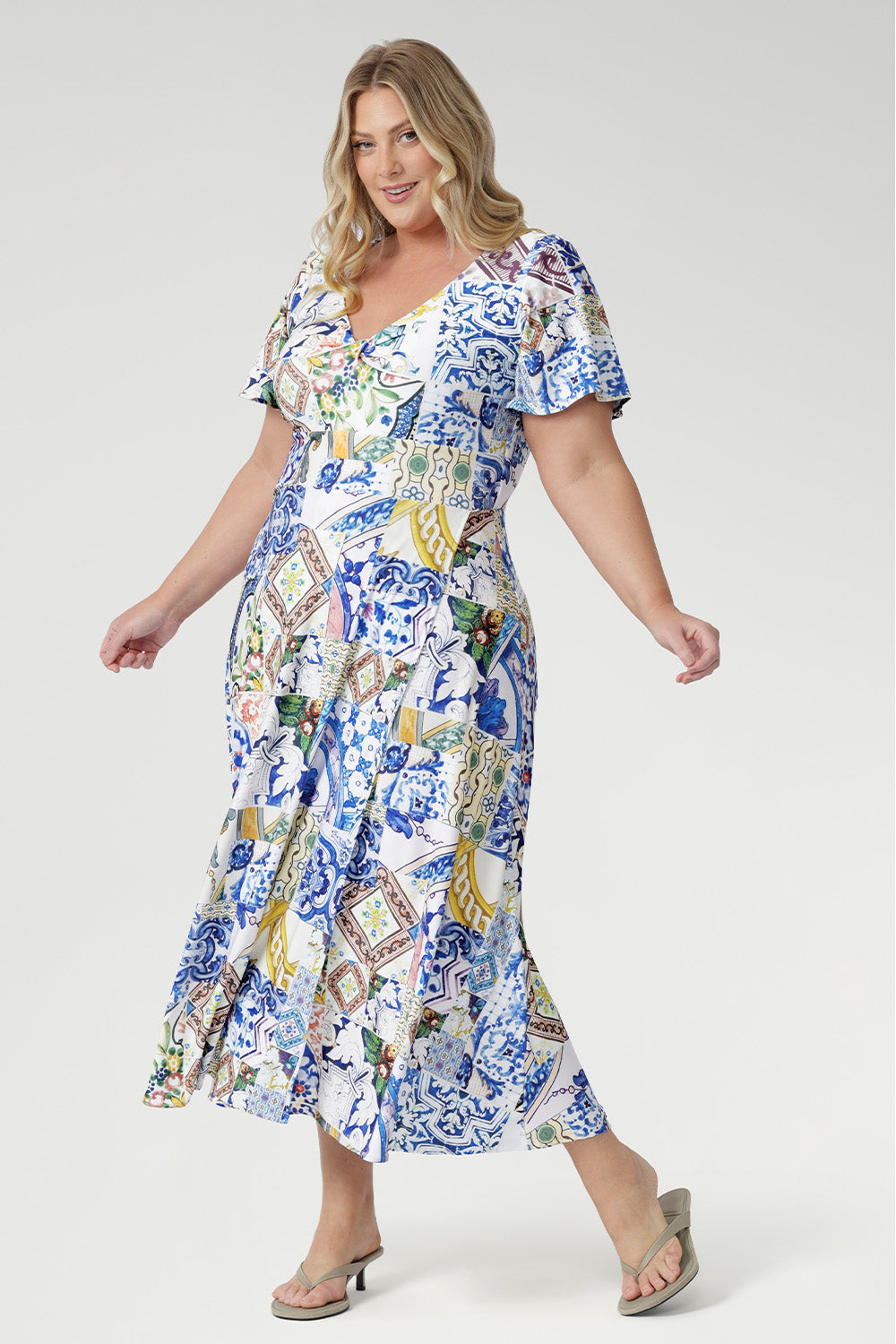 The empire line silhouette and twist-front V-neckline create a flattering fit, complemented by flutter sleeves and a double-layered bodice for gentle coverage. Finished with a flowing overlap-style skirt, this maxi dress moves beautifully from daytime events to evening celebrations with effortless sophistication.