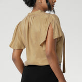 Woven blouse made from luxurious gold soft suede-touch Tencel fabric. This images features a blouse draped beautifully on the body, catching the light in the most flattering way. Though the fabric has no stretch, it offers an effortlessly graceful silhouette that moves with you, creating a striking and sophisticated look. Available in size 8-24.