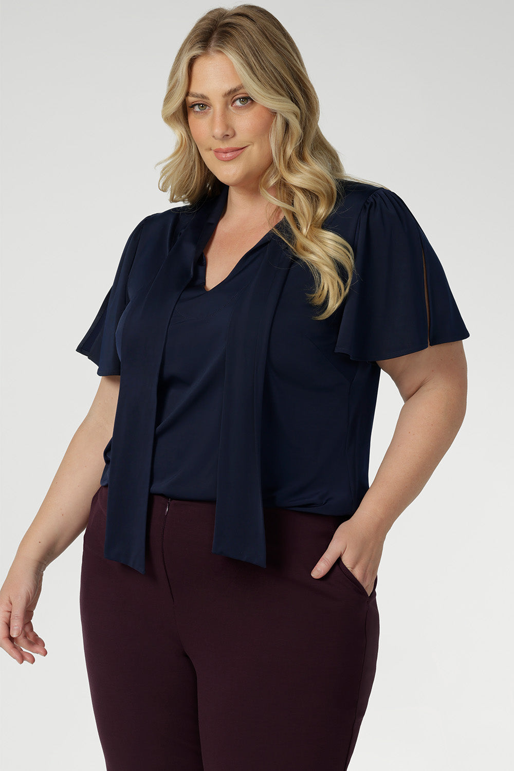 Close up image of plus size woman wearing navy work wear blouse. This top is navy in colour and has been designed using high quality easy care dry touch jersey material. Garments are Australian made by Leina + Fleur for Australian and New Zealand woman.