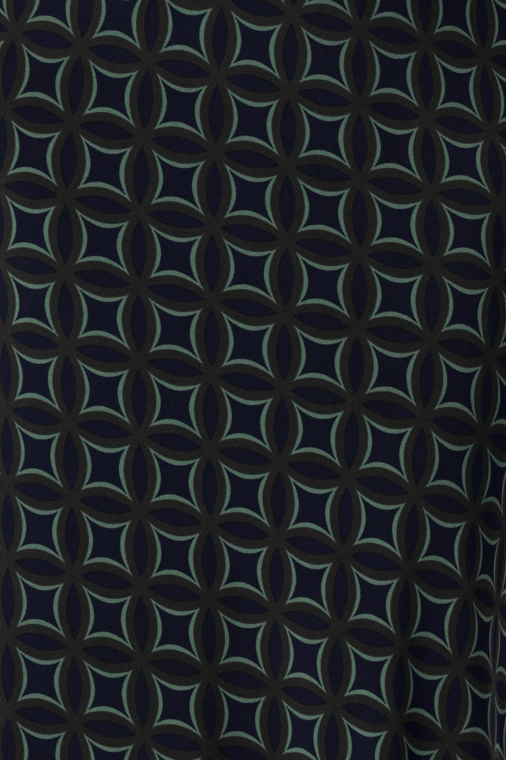 The Midnight Mosaic print is crafted on a dry touch jersey base in Navy, with geometric details in shades of green and grey. The fabric has a soft stretch. Image swatch of Midnight Mosaic print used to create Australian made woman's workwear clothing.