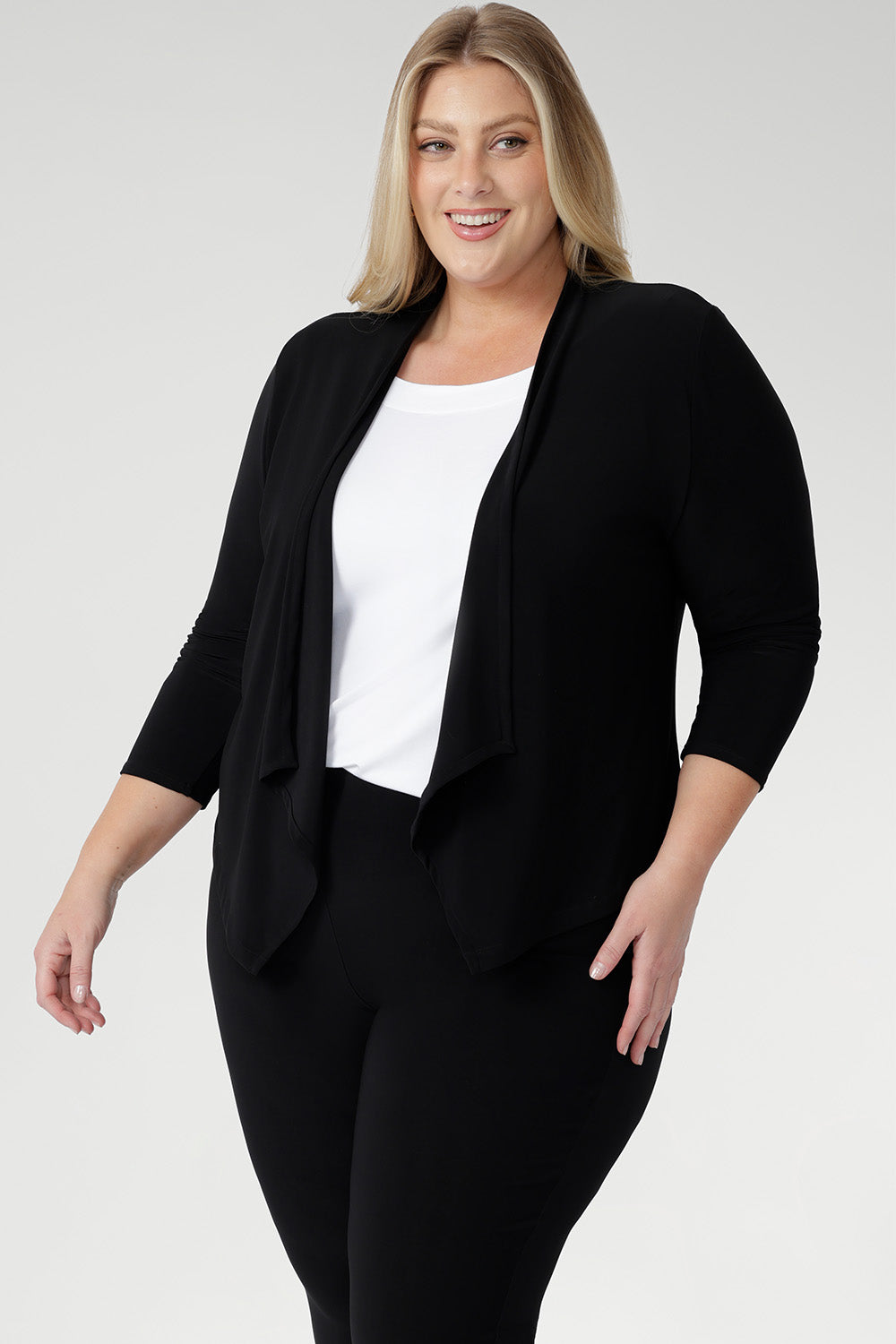 Woman wears a a black waterfall front jacket/ cardigan over a white top and black pants for casual and chic weekend comfort.