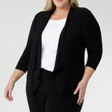 Woman wears a a black waterfall front jacket/ cardigan over a white top and black pants for casual and chic weekend comfort.