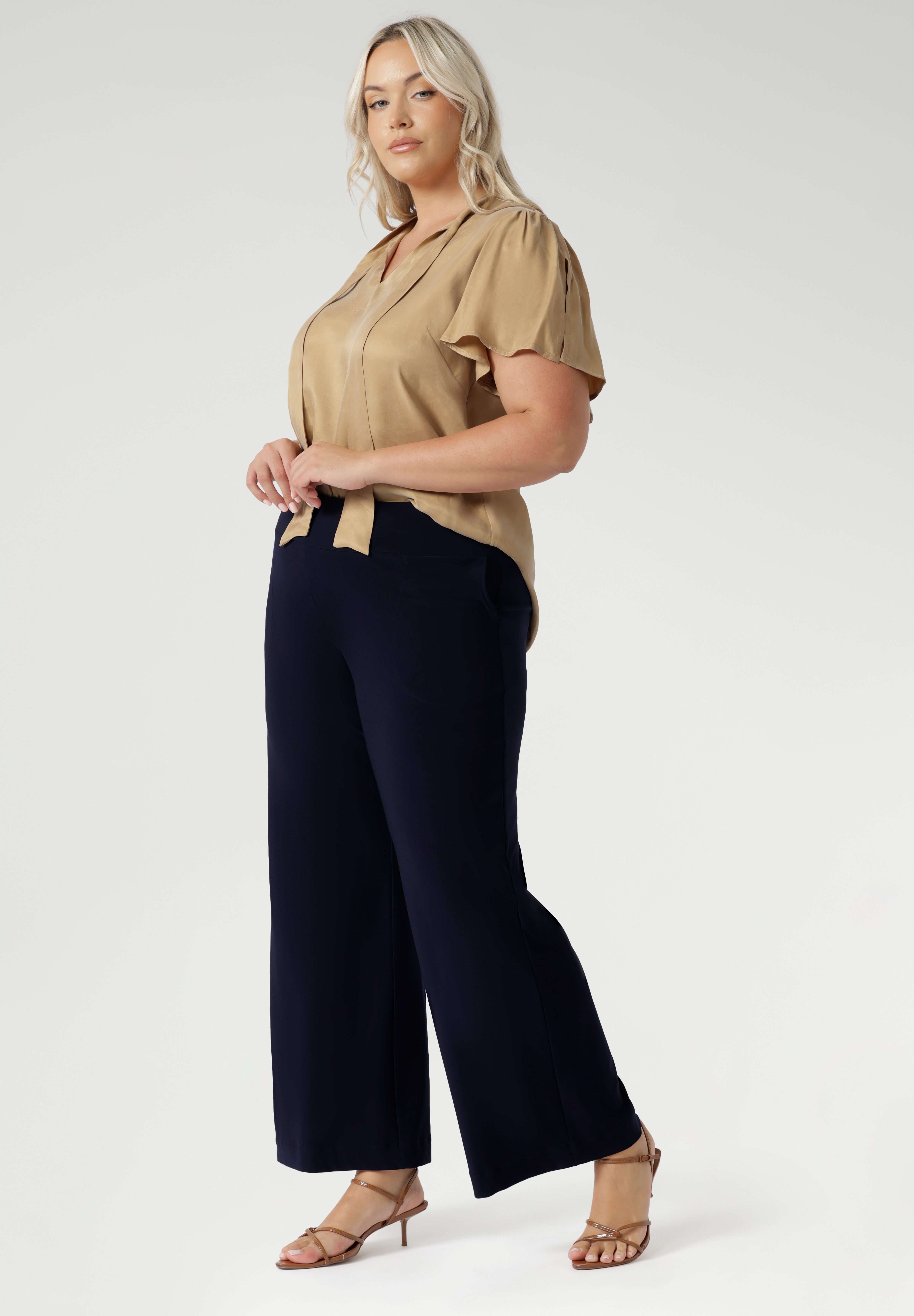 Women's size inclusive work pants. Pictured on a size 18 woman, these comfortable navy corporate pants. Full length navy, straight leg pants with stretch. Shop in sizes 8-24. Plus size woman wears the Monroe Pants Navy in the regular length.