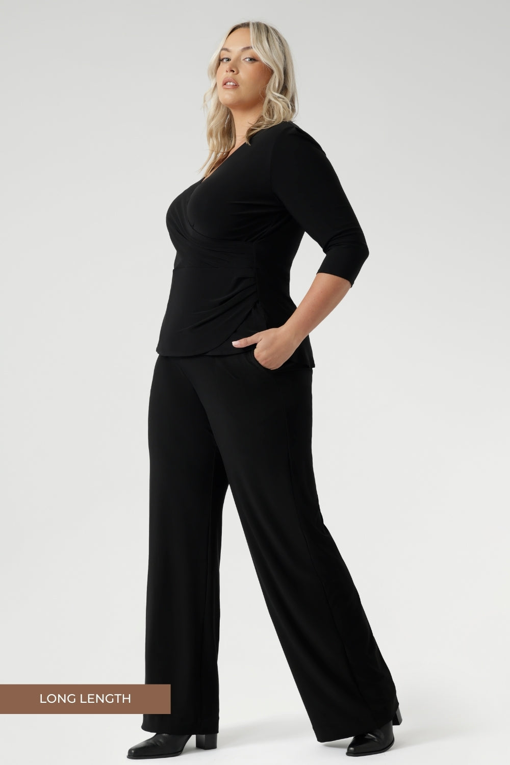 Plus size model wears black pull on pants in long length. Classic black pants are a pull on style for easy care & wear. Leina & Fleur stock these pants in sizes 8-24 and in 3 height lengths.