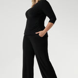 Plus size model wears black pull on pants in long length. Classic black pants are a pull on style for easy care & wear. Leina & Fleur stock these pants in sizes 8-24 and in 3 height lengths.