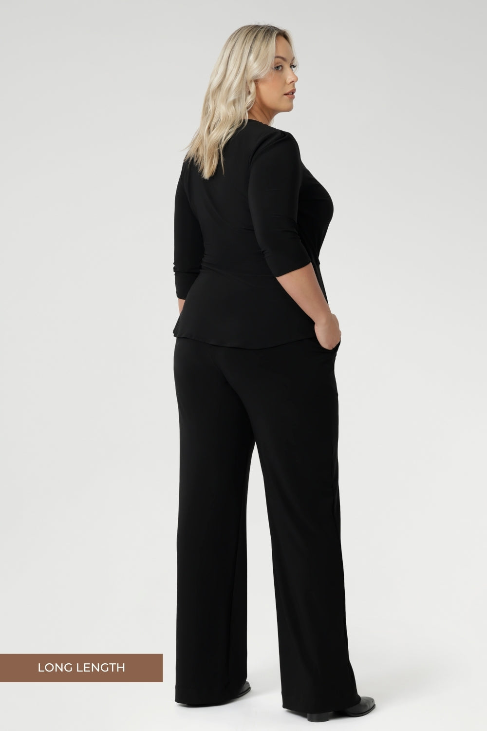 Plus size model wears black pull on pants in long length. Classic black pants are a pull on style for easy care & wear. Leina & Fleur stock these pants in sizes 8-24 and in 3 height lengths.
