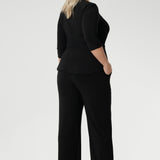 Plus size model wears black pull on pants in long length. Classic black pants are a pull on style for easy care & wear. Leina & Fleur stock these pants in sizes 8-24 and in 3 height lengths.