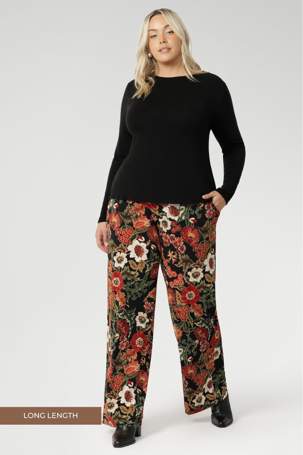 Monroe Pant effortlessly transitions from work to weekend with ease. Made in Australia, these pants combine sophistication and practicality. Tall woman wears floral printed pants with black work top. Size 18 model wears long length Monroe Pants.