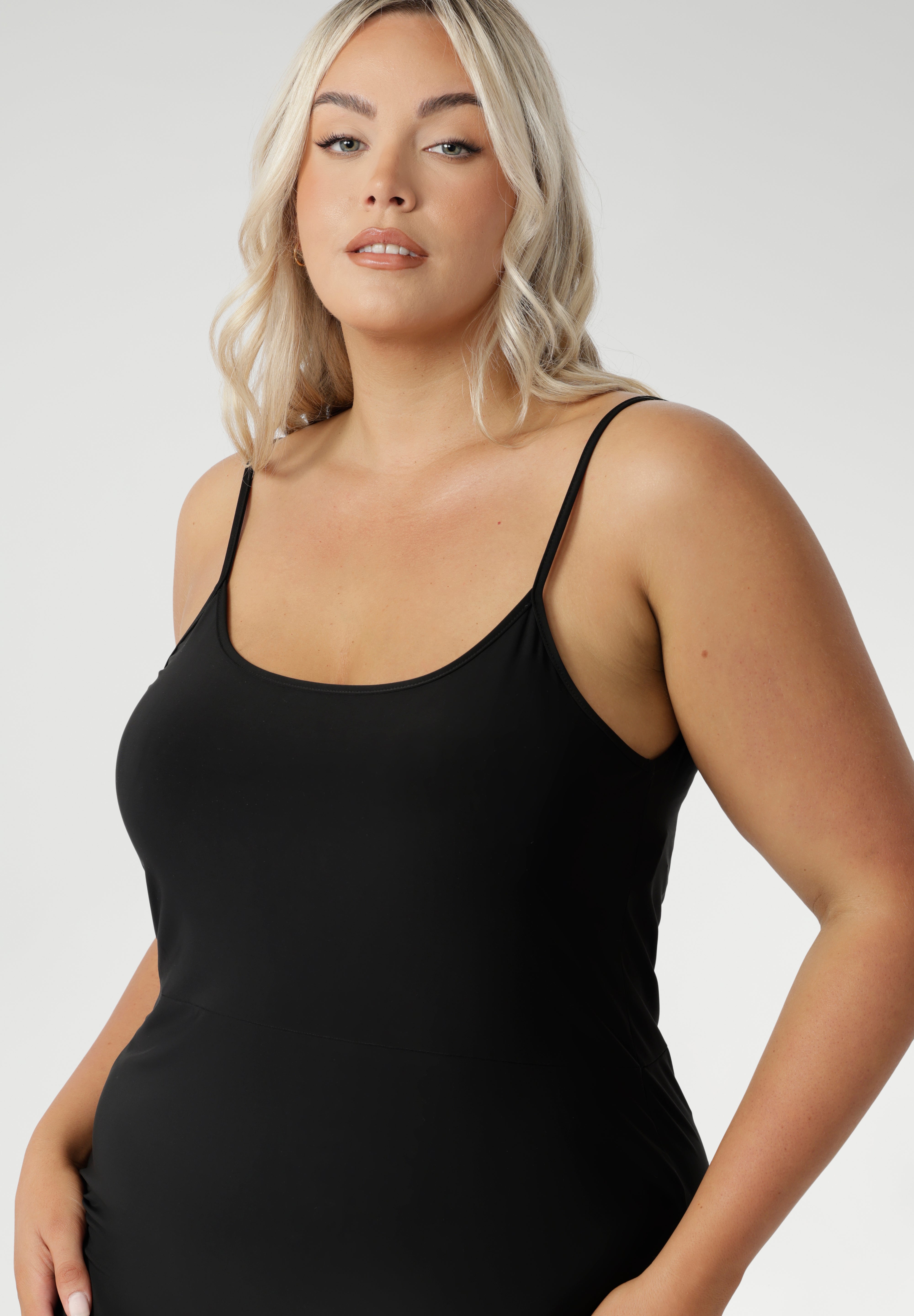 Fully reversible for multiple styling options, it’s the perfect base layer to wear under dresses or separates for smooth, comfortable coverage. Black slip dress for women is seen on size 18 woman with round neck front facing.