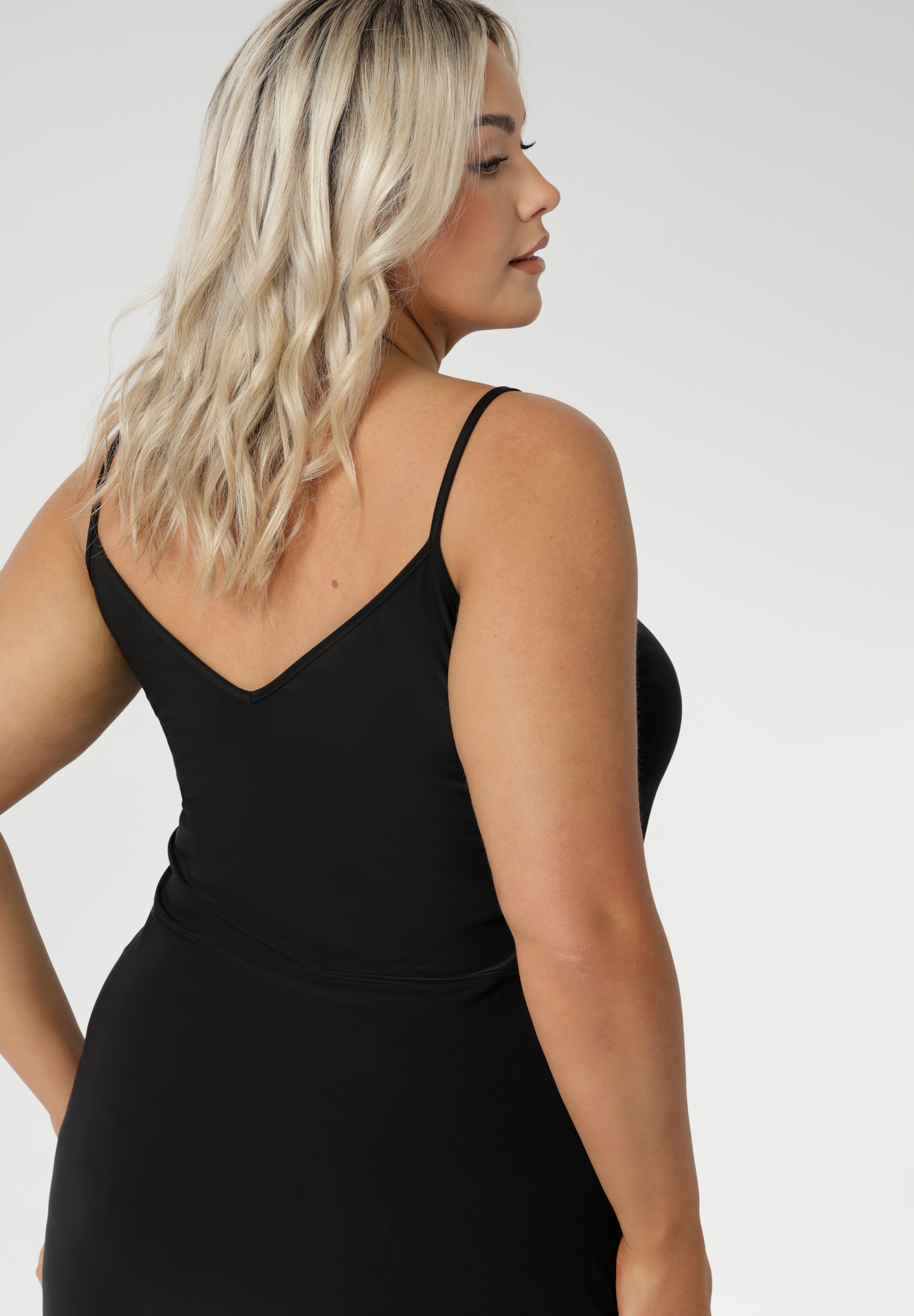 Black slip dress for women is seen on size 18 woman with Vneck back facing. Reversible for multiple styling options. Perfect base layer to wear under dresses or separates for smooth, comfortable coverage & warmth.