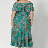 Back view of a woman wearing the Myla dress in Jade Safari off shoulder frill neck style. Side pockets and frill hem. Made in Australia and size inclusive for women size 8-24.