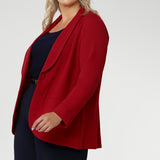 Plus size woman wears the Merit Blazer in Flame, a textured scuba crepe blazer with button front. This red work blazer is worn with red workwear pants and red cami top. Curved hemline and front pockets. Made in Australia for women size 8 - 24.