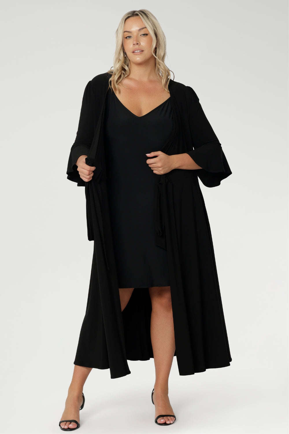 Plus size model wears our mini-length reversible slip in classic black jersey, showcased under a wrap dress. Crafted from soft, stretch jersey fabric, this essential layering piece features thin straps and a flattering V-neckline worn at the front.