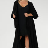 Plus size model wears our mini-length reversible slip in classic black jersey, showcased under a wrap dress. Crafted from soft, stretch jersey fabric, this essential layering piece features thin straps and a flattering V-neckline worn at the front.
