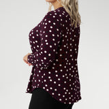 The long sleeves are finished with a refined cuff, creating a polished, professional look ideal for work or smart casual wear. Plus size model wears her burgundy blouse with black women's work pants.