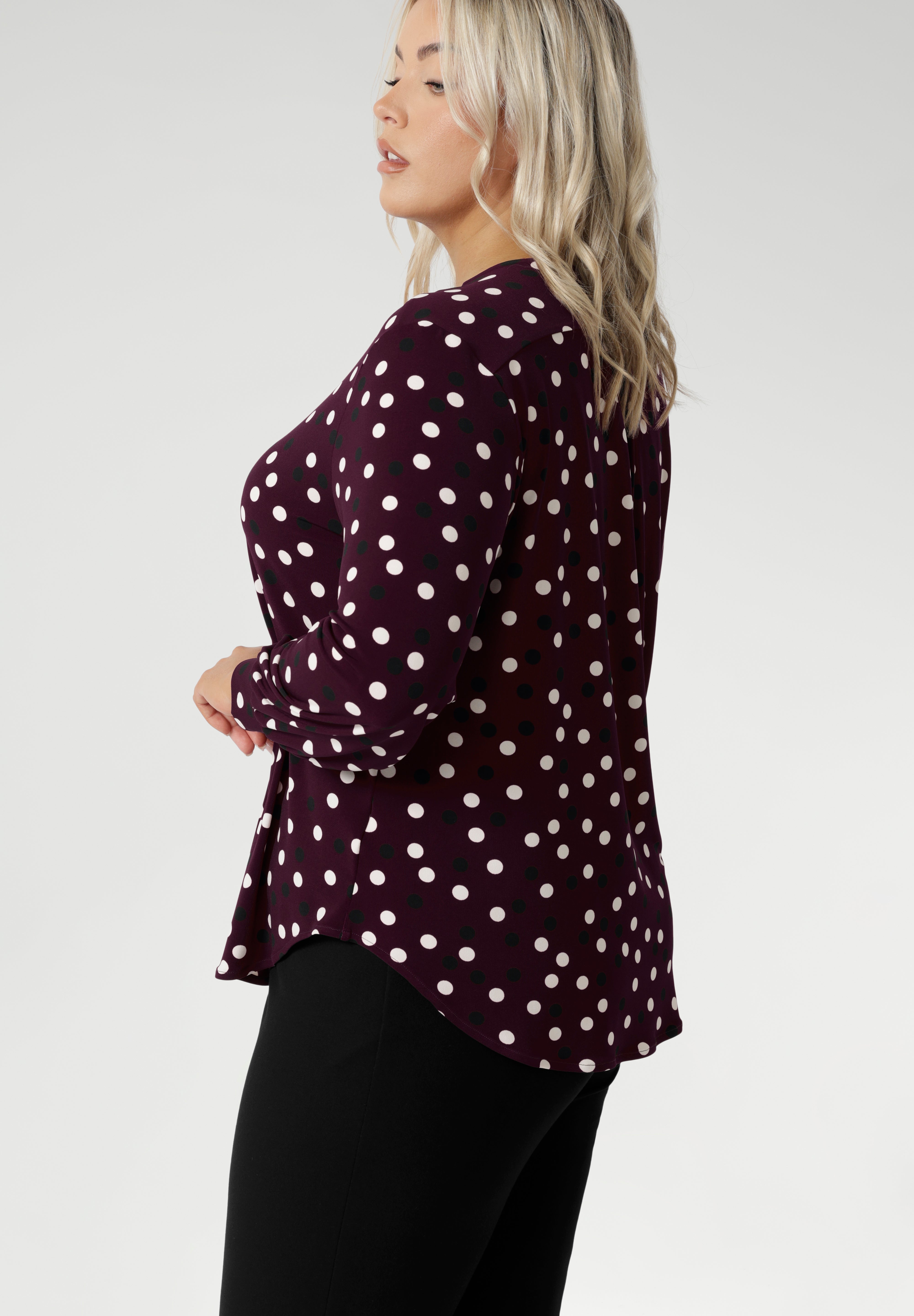 The long sleeves are finished with a refined cuff, creating a polished, professional look ideal for work or smart casual wear. Plus size model wears her burgundy blouse with black women's work pants.
