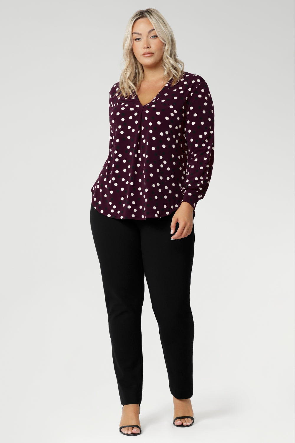 A flattering V-neckline is enhanced by a precisely placed tailored tuck at the centre front, adding both structure and shape. The long sleeves are finished with a refined cuff, creating a polished, professional look ideal for work or smart casual wear. At the back, a shoulder yoke flows into a centre-back tuck, offering subtle detail and a touch of sophistication.