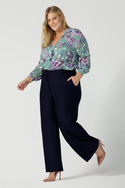 A size 18 woman wears the Kade tailored pant in Navy. Made in Australia for women size 8 - 24. Styled back with the Paeton top in day bloom. V-necline with pleat front and bind. Made in Australia for women size 8 - 24. 