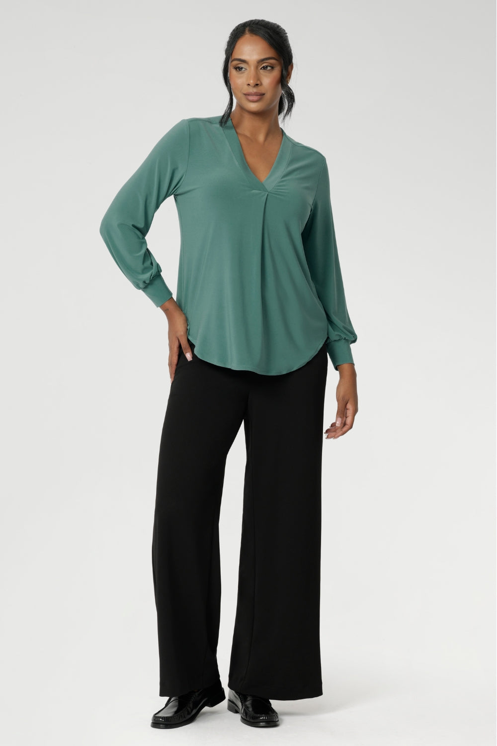 Finished with a curved shirttail hemline, the Paeton is ideal for workdays, weekend styling, and effortless layering. Available in sizes 8 to 24. Size 10 woman wears her Paeton Top in Menthol untucked over black wide leg trousers.