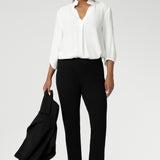 A size 10 woman wears the Paxton Pant in black. A loose fitting ponte pant in black. A slack pant with cropped length. Made in Australia for women size 8-24. Styled back with the Arley Top in white.
