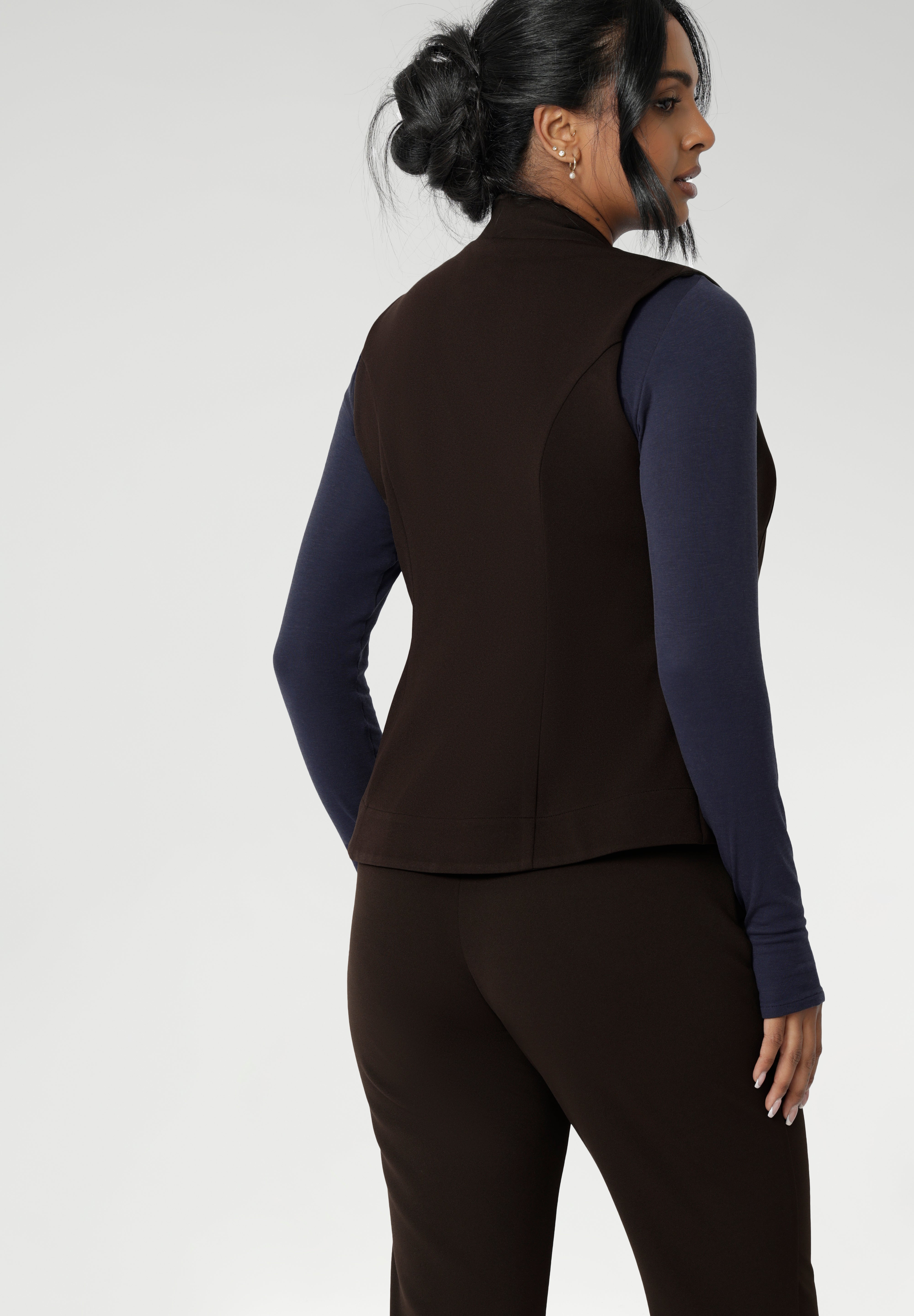 The fitted vest features a flattering V-neckline, sleeveless design, and a two-way opening zip for added flexibility. It also includes back side panels for a tailored fit and is available in sizes 8-24.