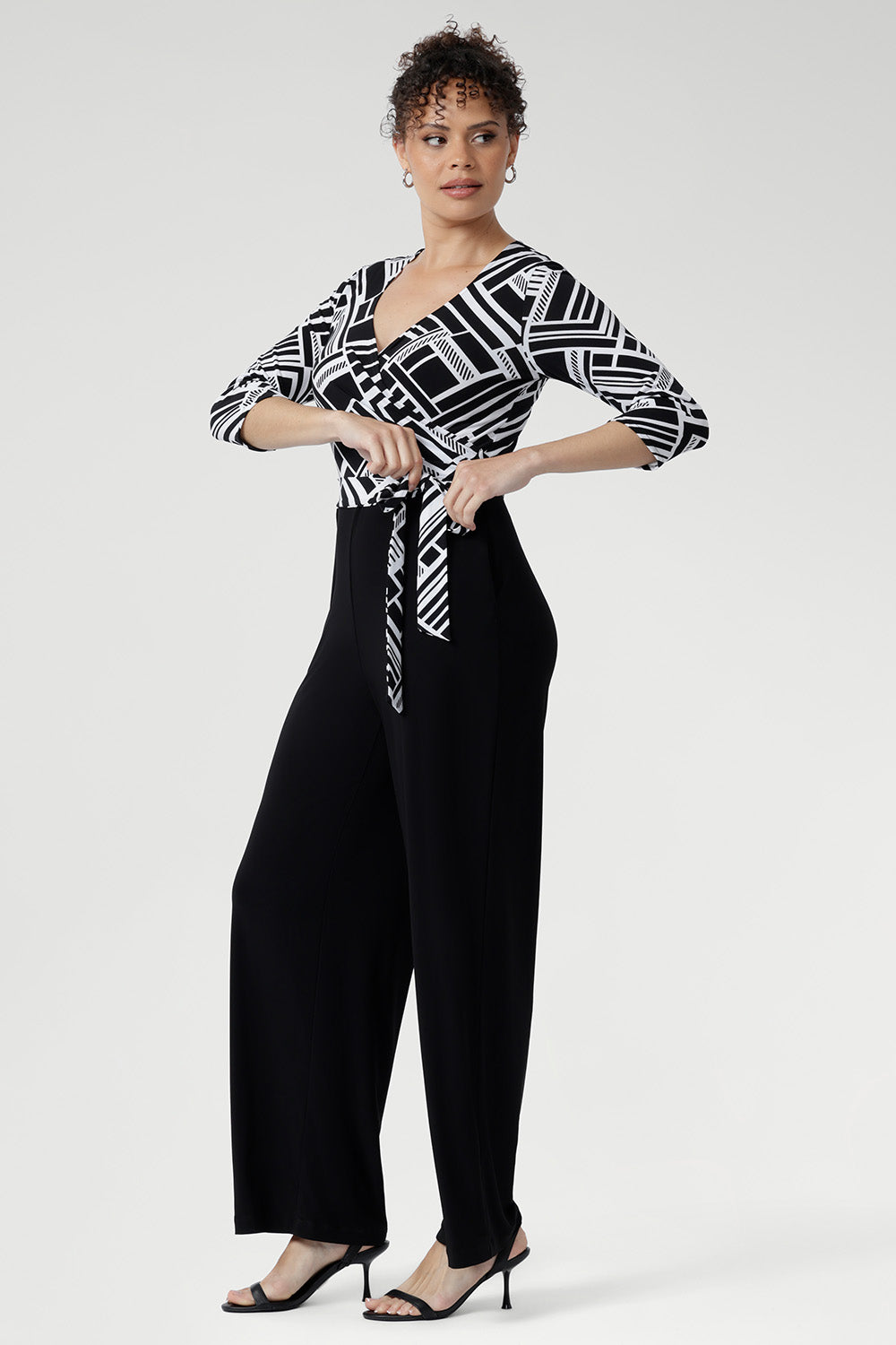 Showcasing a striking black and white geometric print across the wrap-style bodice, this jumpsuit features a flattering self-tie waist and a double-layered back for a refined and supportive fit.