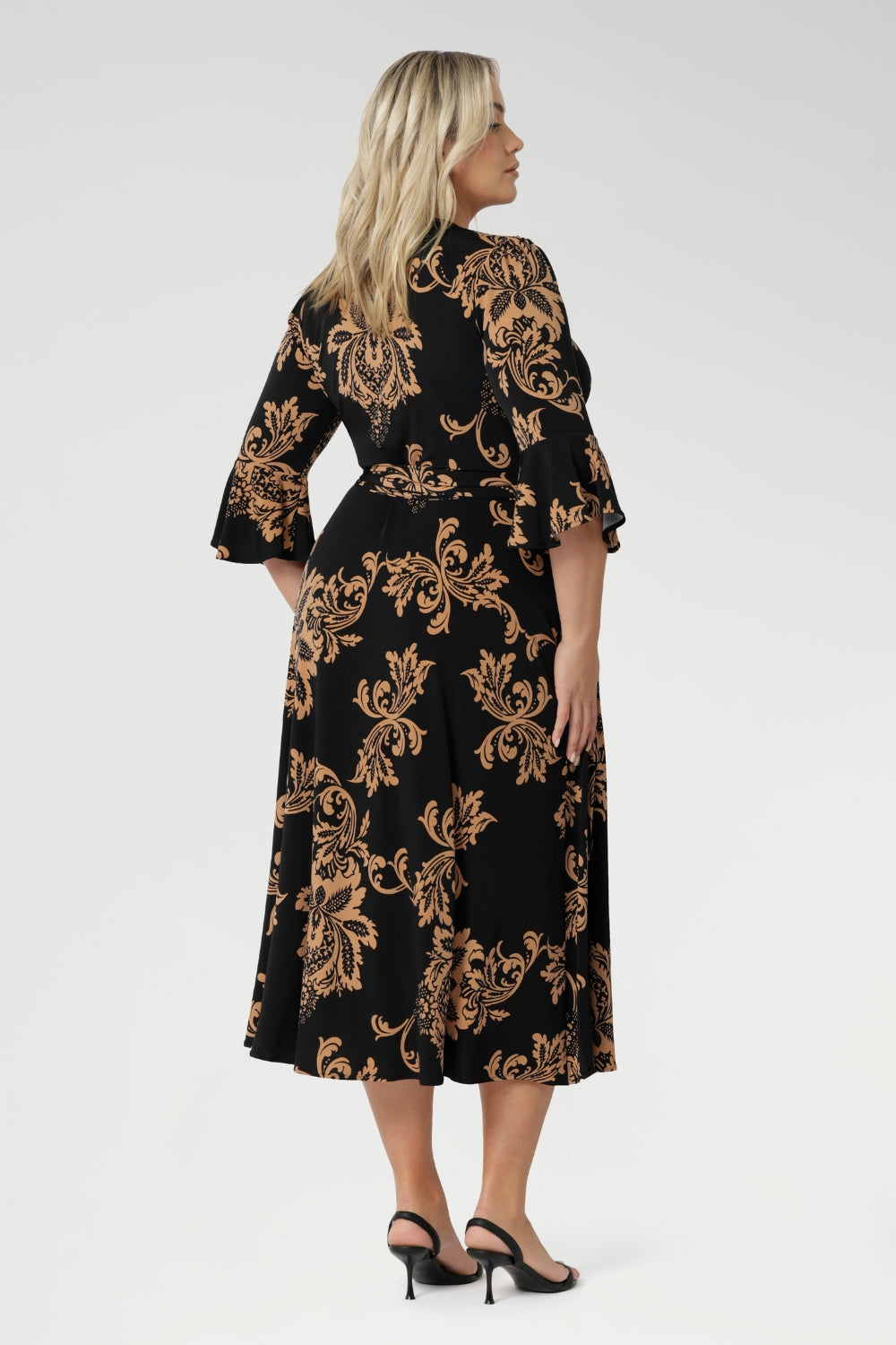 Size 18 woman wears her Portia Dress with black kitten heels. Printed jersey dresses proudly made in Australia and available in sizes 8 to 24. Made with easy care fabric that provides stretch and comfort.