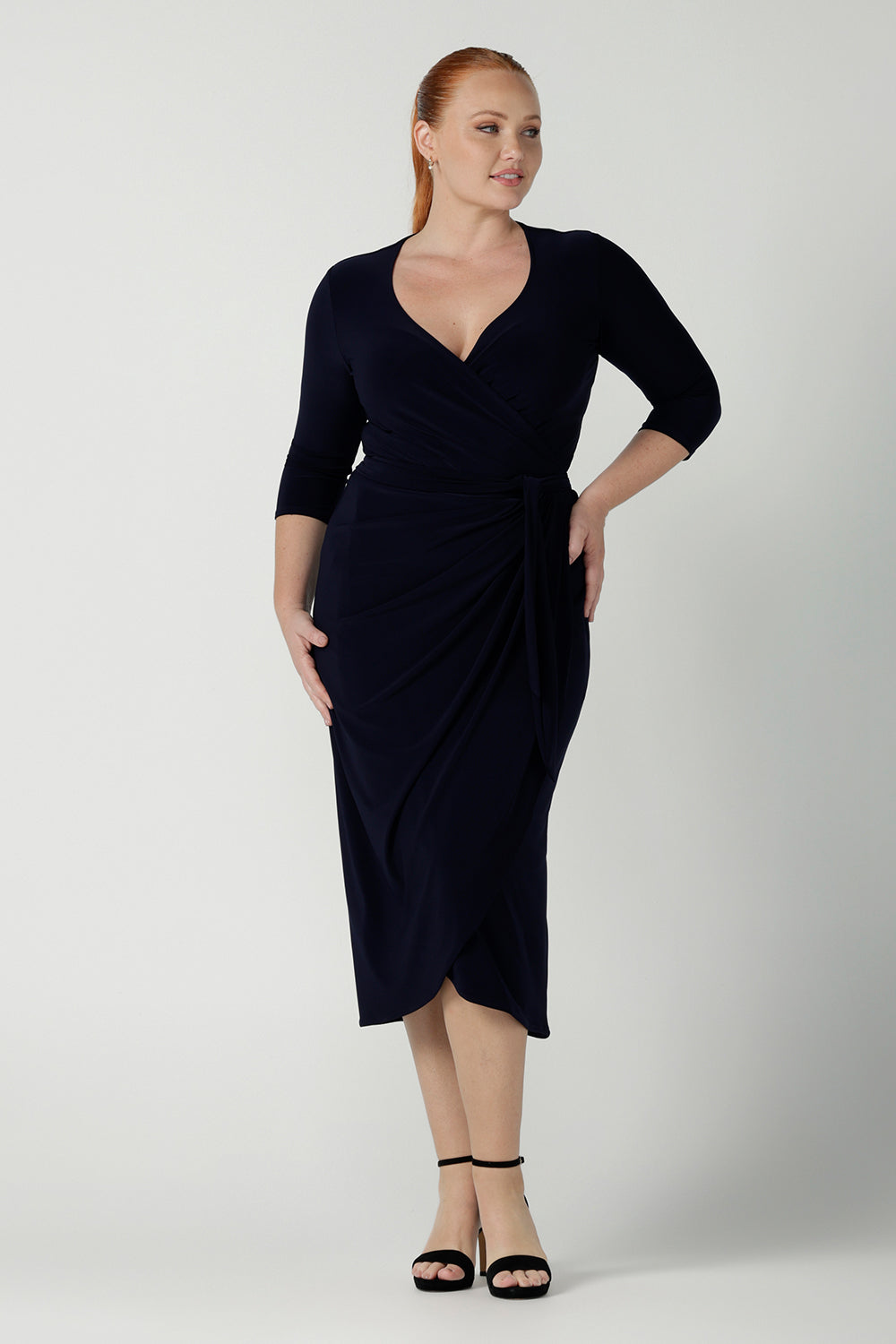 Size 12  woman wears the Robin dress in Navy. Midi length with 3/4 sleeves. V-neckline with a functioning wrap. A great work to weekend piece. Made in Australia for women size 8 - 24.