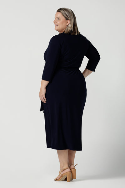 Back view of a size 18 curvy woman wears the Robin dress in Navy. Midi length with 3/4 sleeves. V-neckline with a functioning wrap. A great work to weekend piece. Made in Australia for women size 8 - 24.