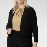 Size 18 woman wears black Jacardi, which is part jacket, part cardigan. This soft touch jacket is a transeasonal cover up. Featuring V-neckline, long sleeves and front buttons. This casual black jacket is made from stretchy and comfortable jersey fabric. Easy care workwear jacket available in sizes 8-24.