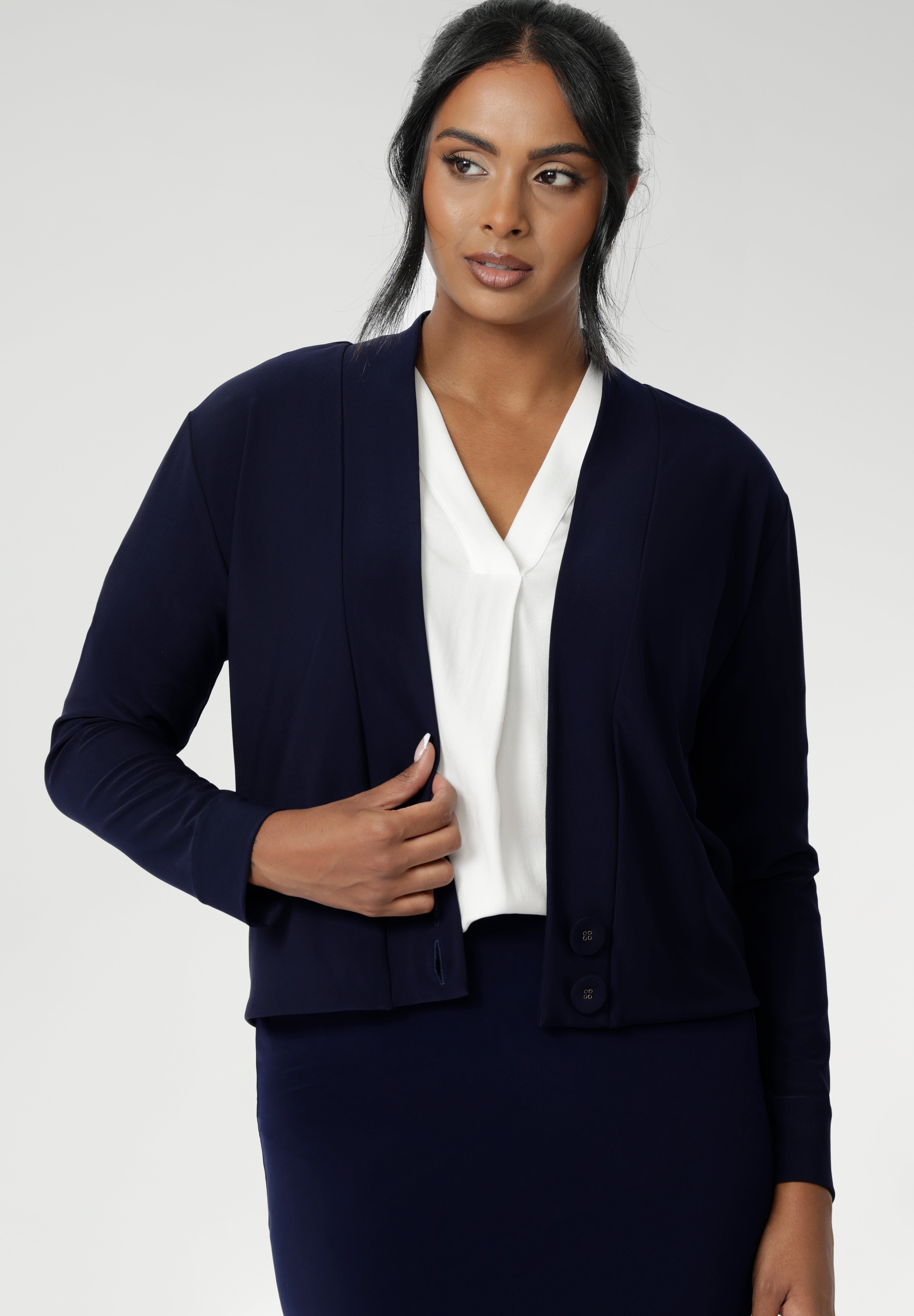 Size 10 woman wears navy jacket/ cardigan. Featuring long sleeves, this jacket-cardigan hybrid is the perfect trans-seasonal cover up for women. Move into the cooler months in style, with this comfortable jacket for workwear and casual layering. Available in sizes 8-24.