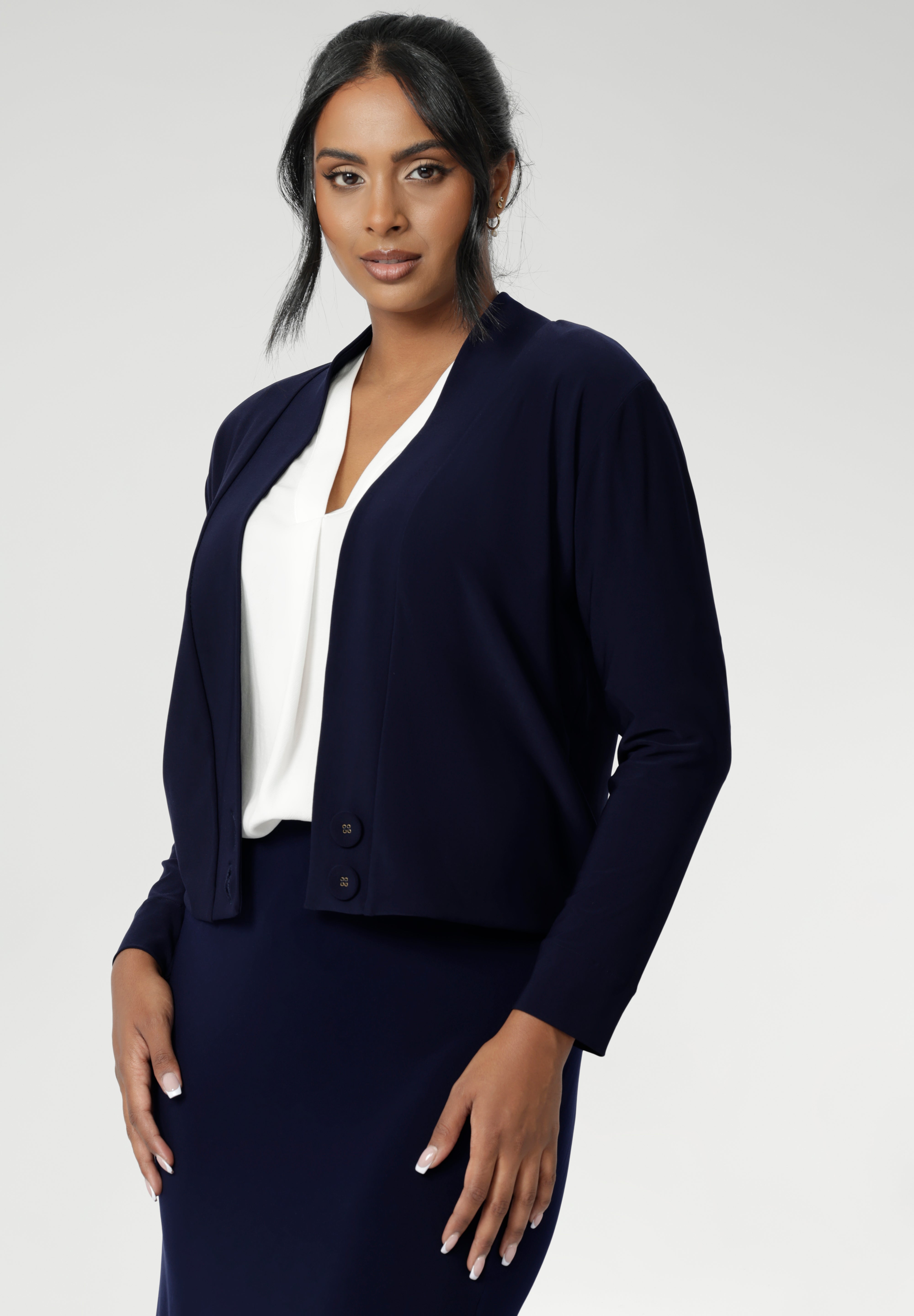 The Jacardi features long sleeves, this jacket-cardigan hybrid is the perfect trans-seasonal cover up for women. Move into the cooler months in style, with this comfortable jacket for workwear and casual layering. Available in sizes 8-24. Size 10 woman wears navy cardigan paired with navy work skirt and white blouse.