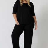 The ultimate outfit for comfortable loungewear, a size 18 woman wears straight wide leg black bamboo lounge pants with a black bamboo slouchy tee top. Thermo-regulating and breathable this is a great pyjama set for night sweats and hot flushes. Shop plus size lounge and sleepwear online at L&F Australia.