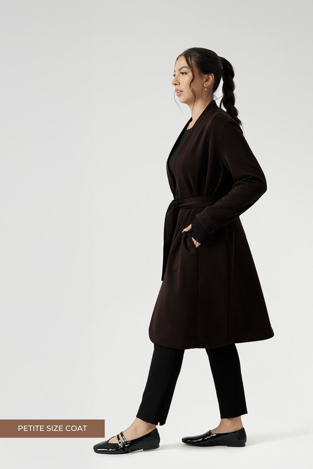 Petite height model wears the Sorel Trench Coat over Paxton Pants & Bryn Top in black for a warmer layer over work wear outfit. The buggy lining at the back ensures added comfort, while the waist seam at the back provides a flattering shape. With belt loops and a fabric waist tie, this versatile trench coat is available in sizes 8-24 and is proudly made in Australia.
