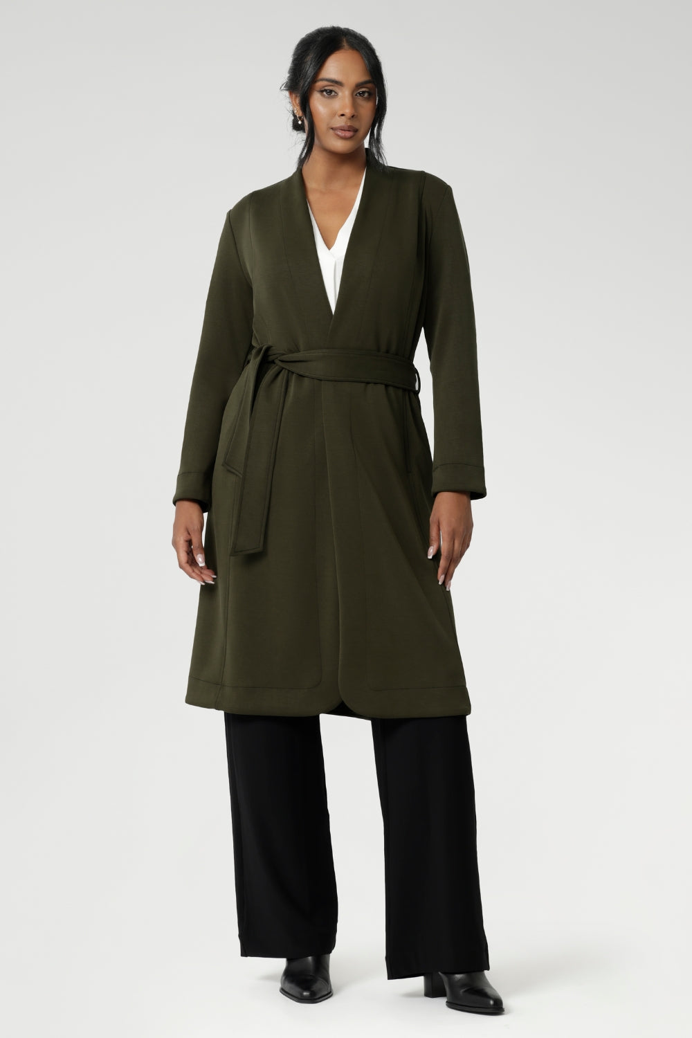 Its grown-on neckline eliminates the need for a collar, offering a sleek, contemporary look. The buggy lining at the back ensures added comfort, while the waist seam at the back provides a flattering shape. With belt loops and a fabric waist tie, this versatile trench coat is available in sizes 8-24 and is proudly made in Australia.